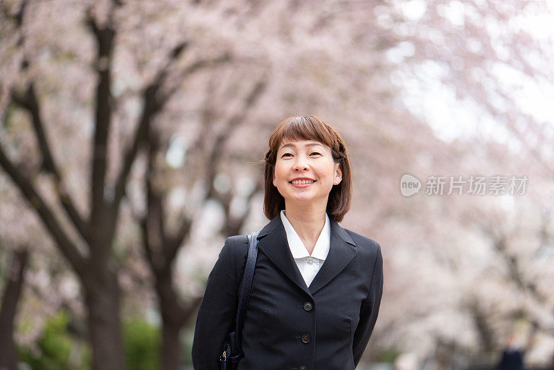 女商人走在樱花盛开的街上