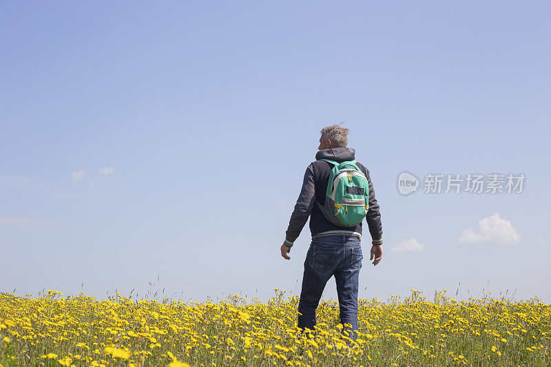 成年徒步旅行者喜欢在春天在美丽的花草地徒步旅行。