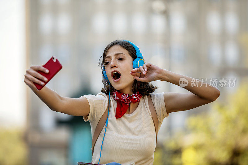 一名年轻女子正带着她的智能手机走在城市的路上