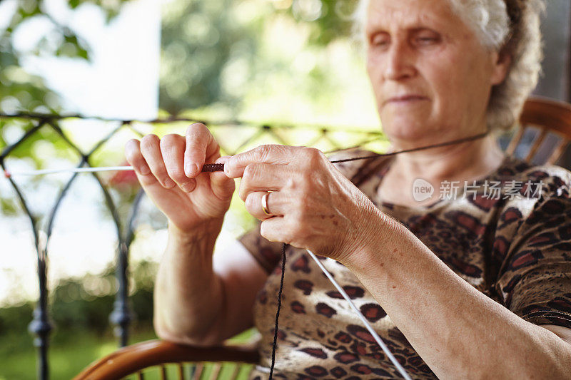 一个阳光明媚的夏日，老奶奶在户外织毛线