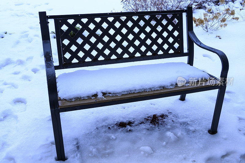 新雪中的脚印和公园长椅
