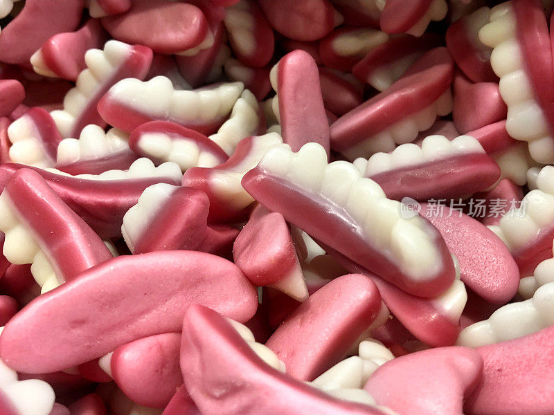 软而耐嚼的乳牙糖果，粉色和白色的假牙糖果在图片和混合容器，果冻牙齿糖果作为糖果在传统的英国糖果店出售，壁纸背景为儿童的糖果，不健康的饮食糖