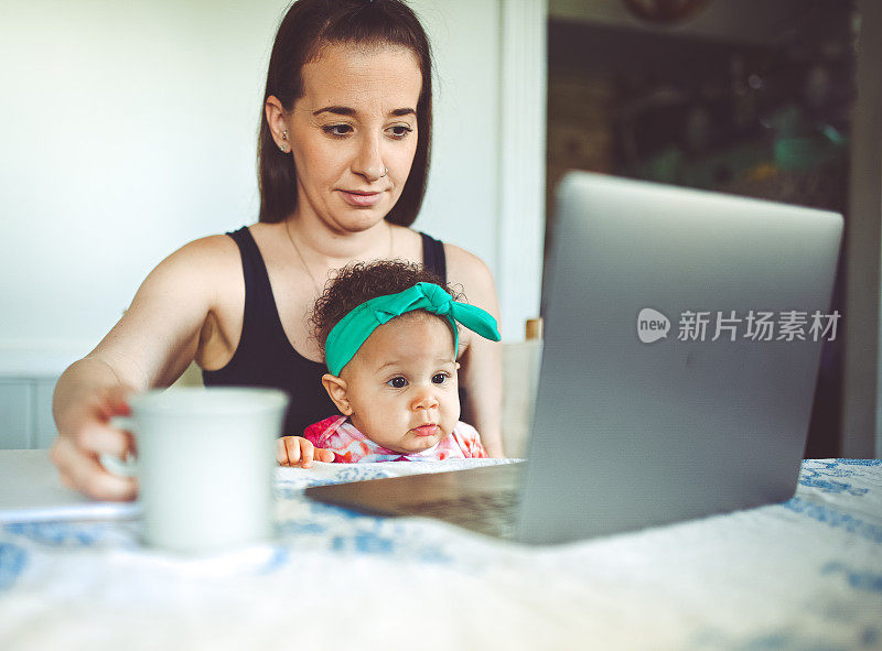 母亲和婴儿坐在家里的笔记本电脑前，工作，视频聊天或远程医疗