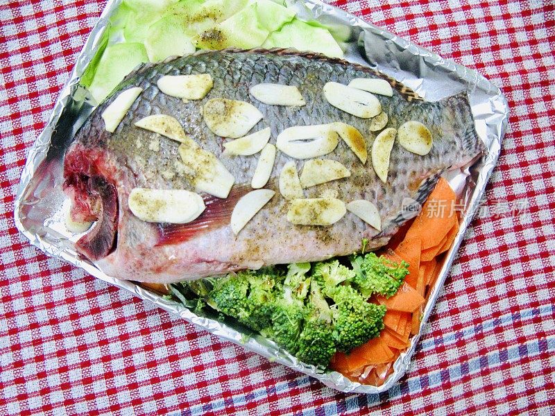 尼罗河罗非鱼配蔬菜和大蒜烤
