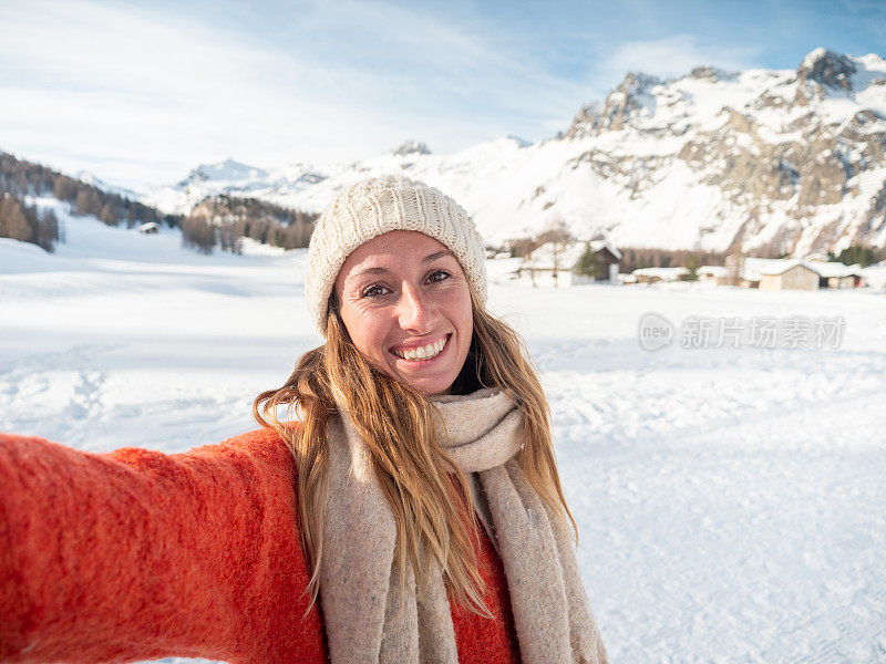 年轻女子在冬天与雪山景观自拍;人们在寒假里玩得很开心