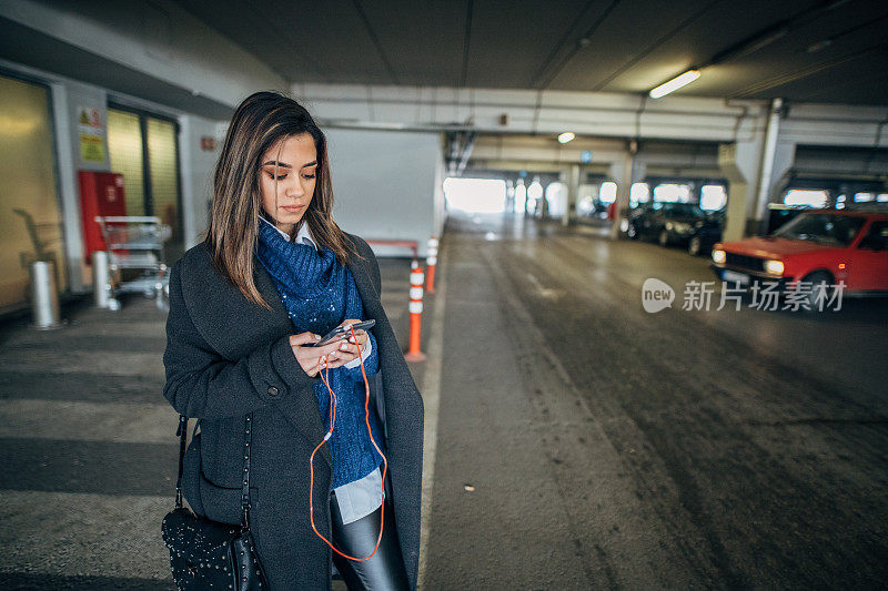 年轻女子在地下车库使用智能手机