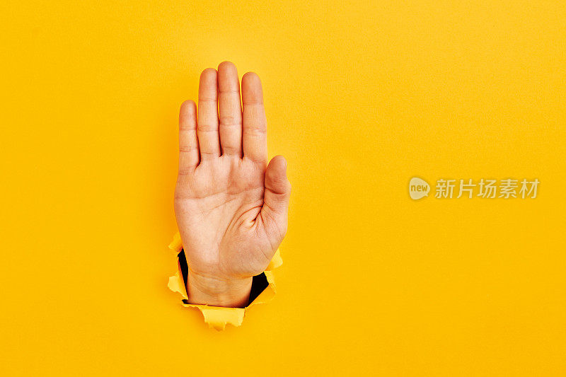 人的手从黄色的“停车标志”纸中伸出来