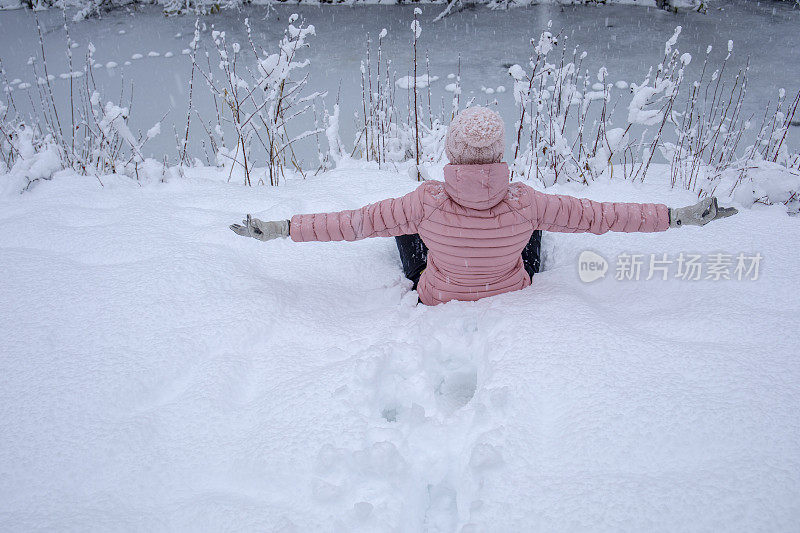 女徒步旅行者在白雪覆盖的河岸放松