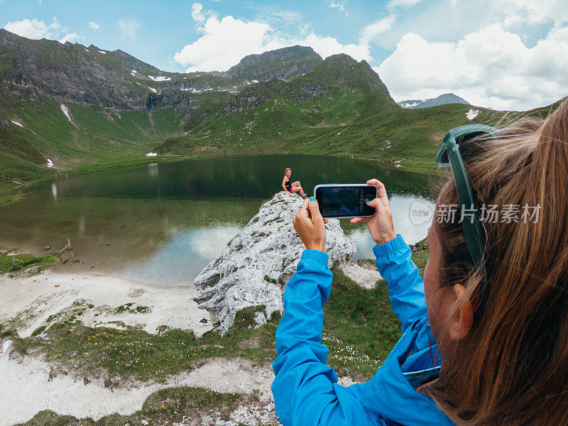 一个女人用智能手机在山间给朋友拍照
