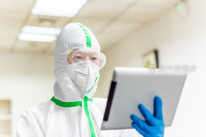 女医生穿着防护服在医生的办公室使用数字平板电脑
