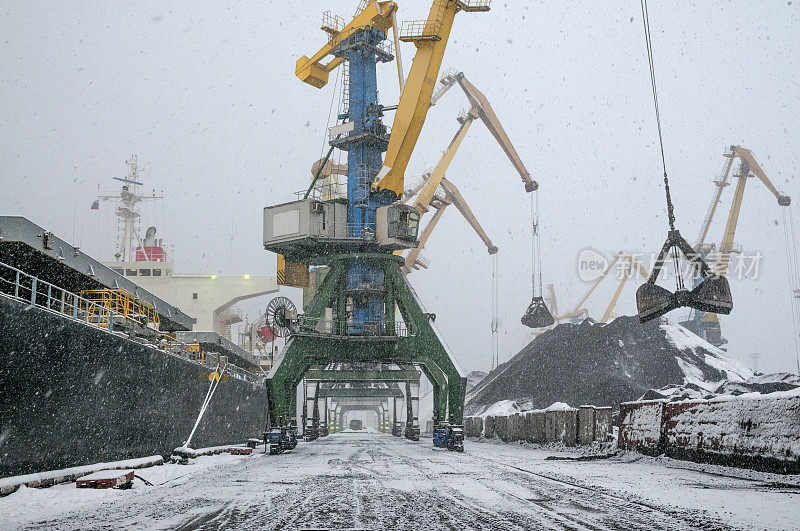 商业海港。在恶劣天气下在工业船的船舱里装煤。