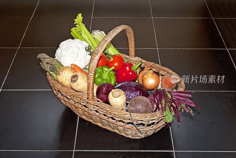 在黑色瓷砖地板上，新鲜的蔬菜堆放在柳条篮子里