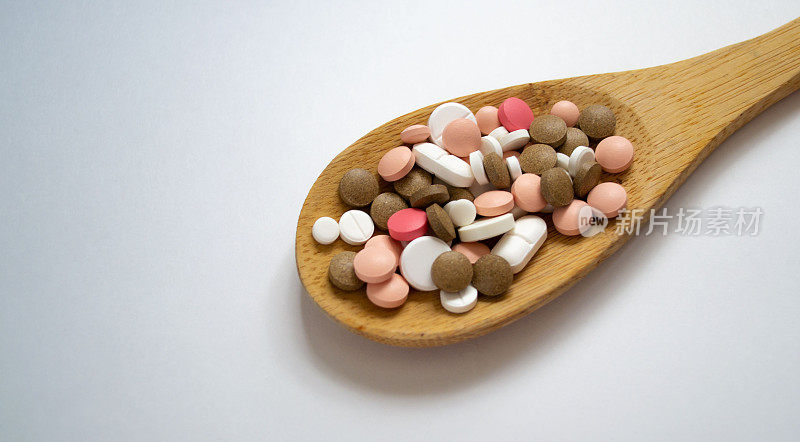 混合药丸、片剂放在木勺上，白色背景上留出文字空间。不同的药片和片剂。药物药丸和药片。平铺的药片和药片