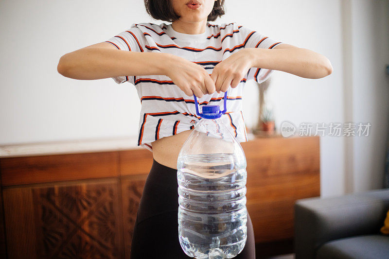 妇女在家里用水瓶锻炼