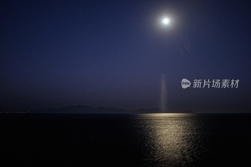 月亮升起在岩石海岸美丽的海面上