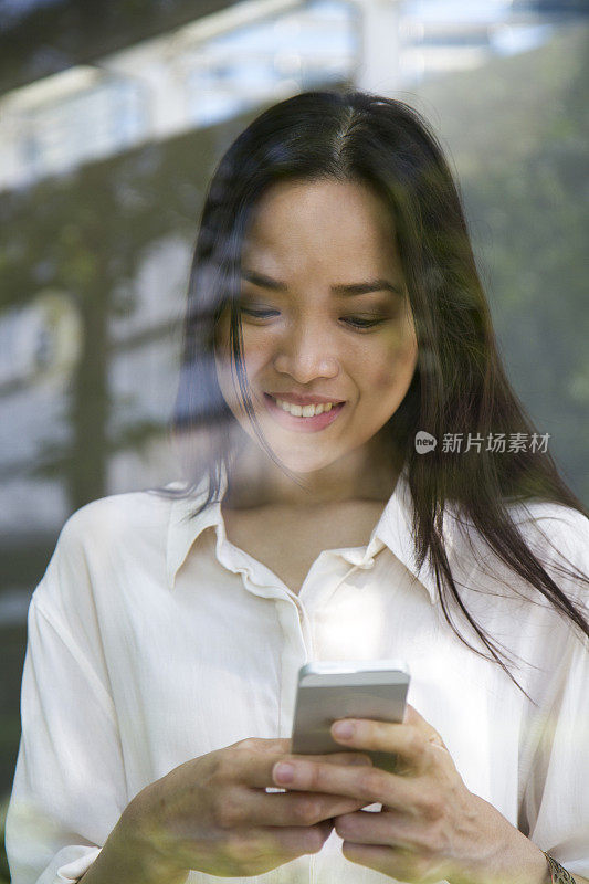 亚洲女人用智能手机发短信。