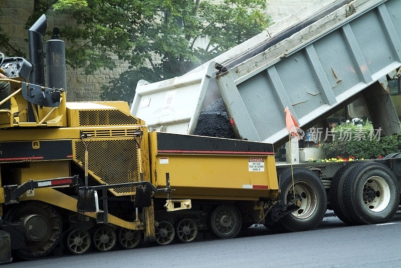 将热沥青倒入铺路机的卡车