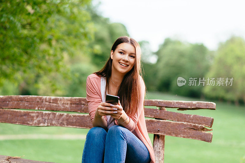 年轻有吸引力的女孩在户外使用电话和微笑