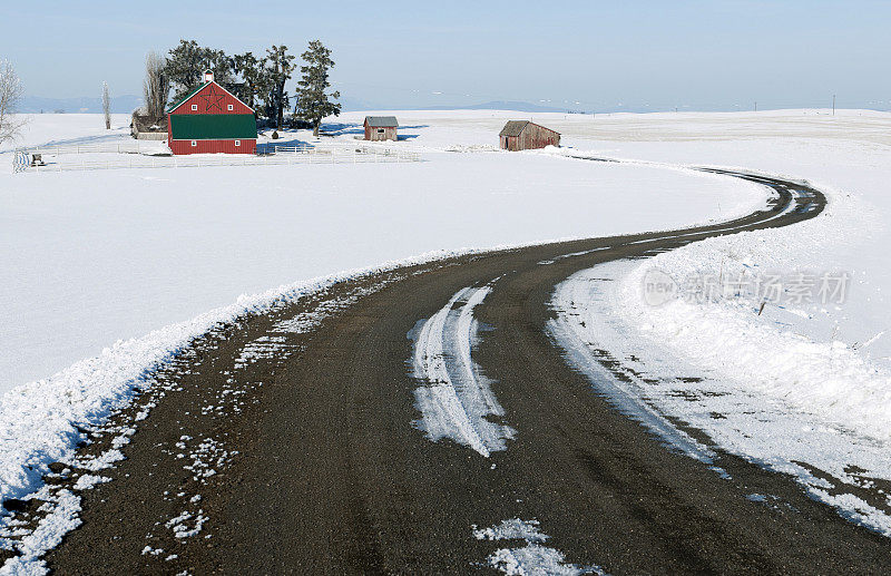 弯曲的道路和谷仓下的雪在华盛顿州东部