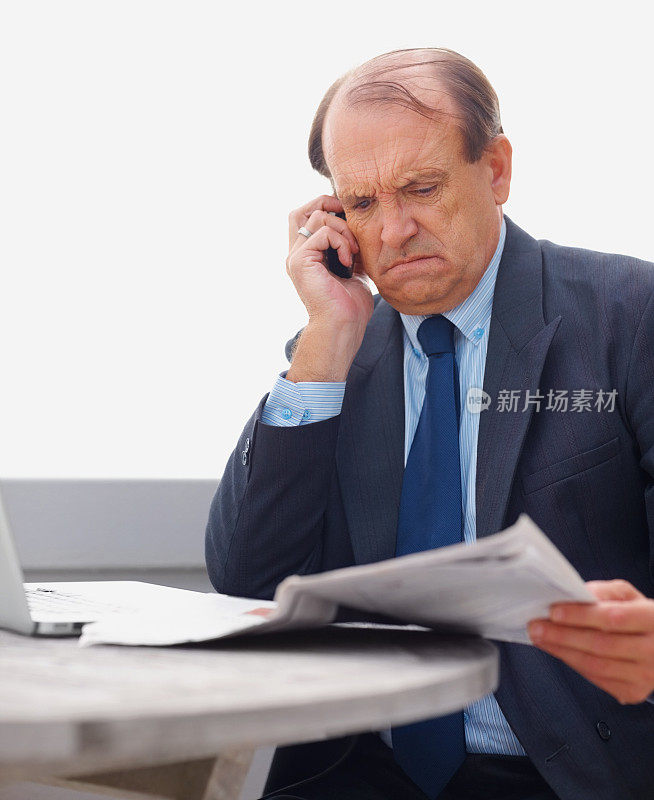 一位愤怒的资深商人正在电话上读报纸