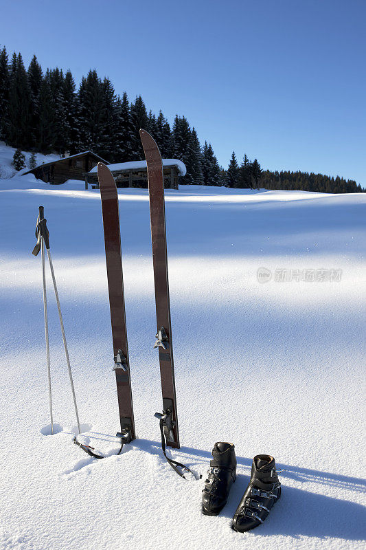 老式的滑雪板、靴子和滑雪杖屹立在新雪中