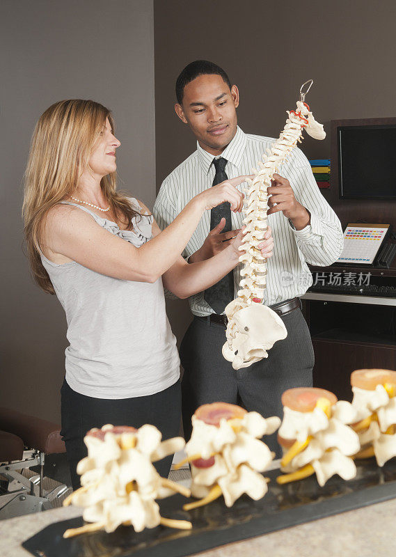 脊椎按摩师向病人展示脊柱模型
