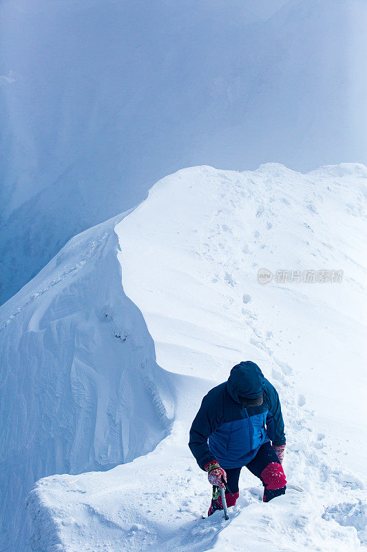 一个人站在冰川山峰上望着云