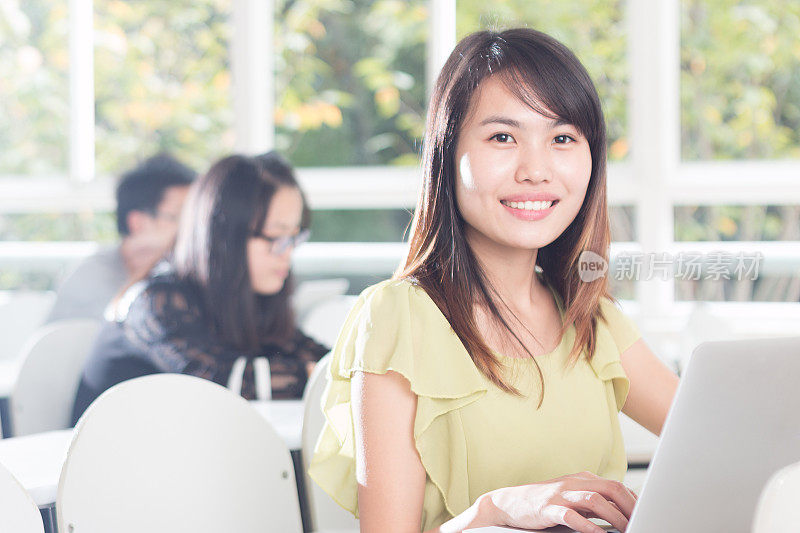 亚洲女孩在教室里用笔记本学习