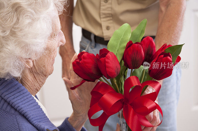 老年妇女收到花束。疗养院的病人。