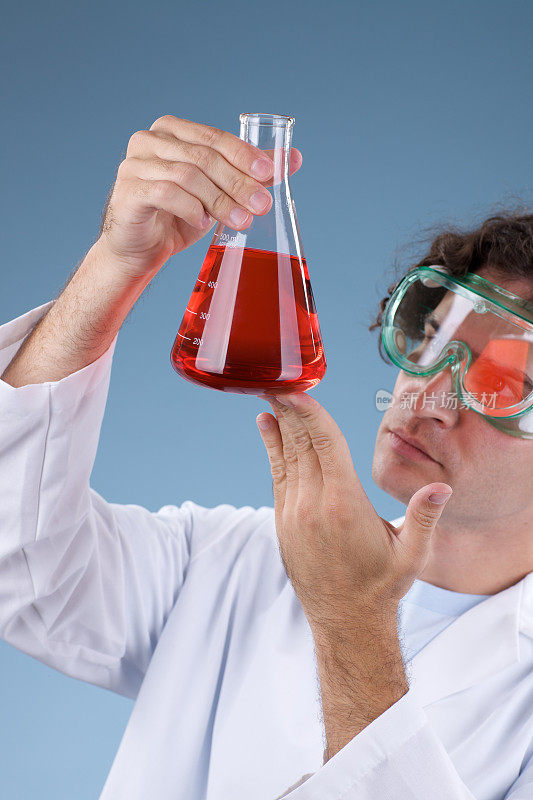 男性科学家观察烧瓶中的红色液体