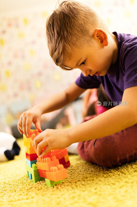 有创意的小男孩在地毯上玩积木。
