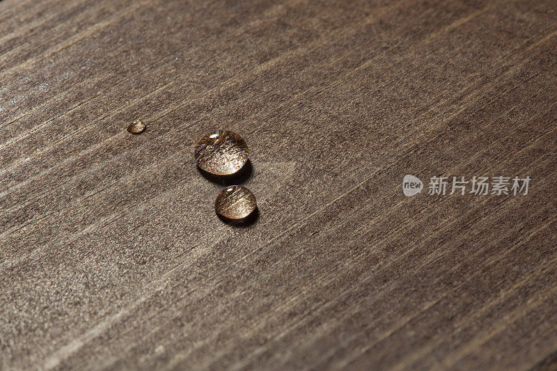 三滴水落在木头表面，特写
