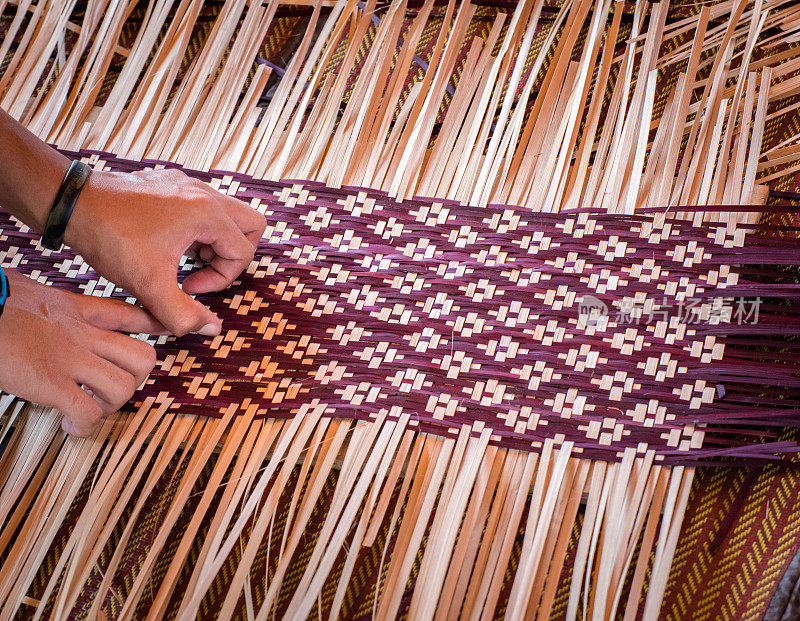 近距离的手编织一个编织垫子泰国的艺术品。