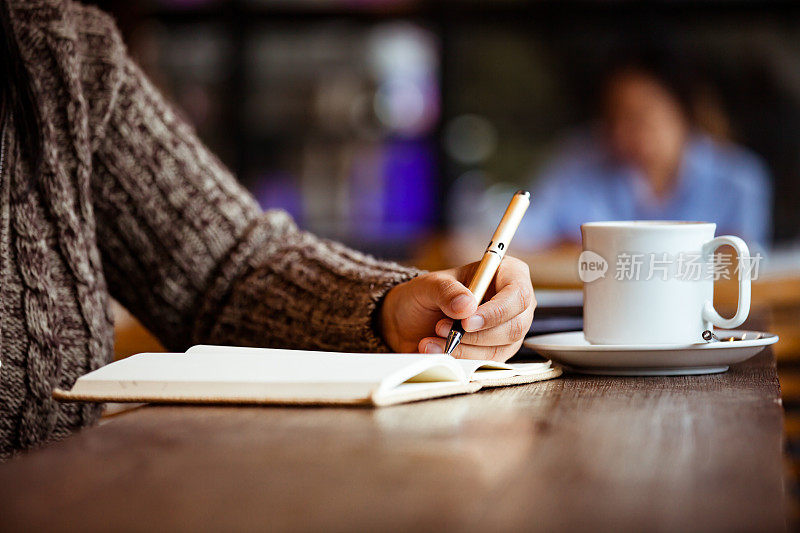 下雨天的咖啡馆里，一个女人在笔记本上写字