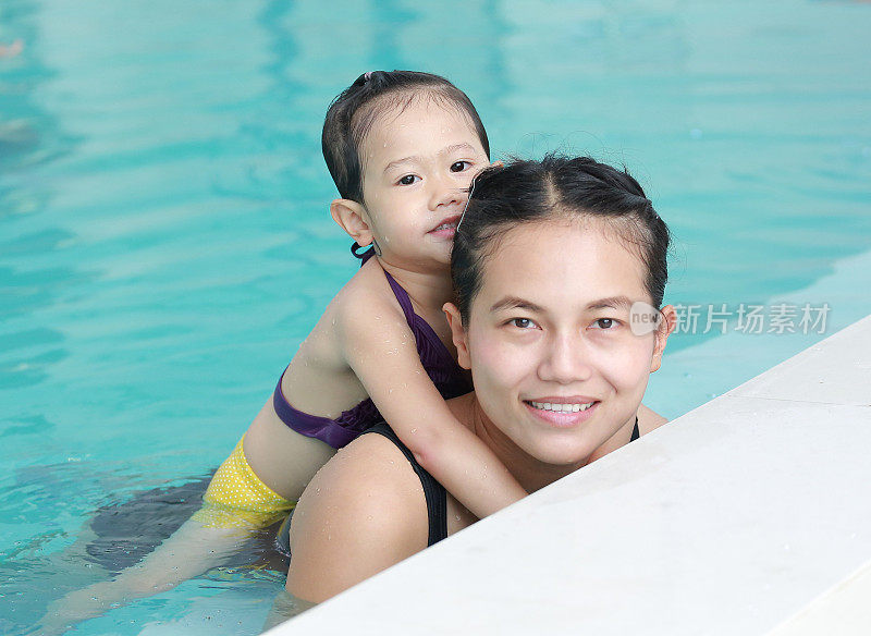 妈妈和小女孩在游泳池里的肖像。