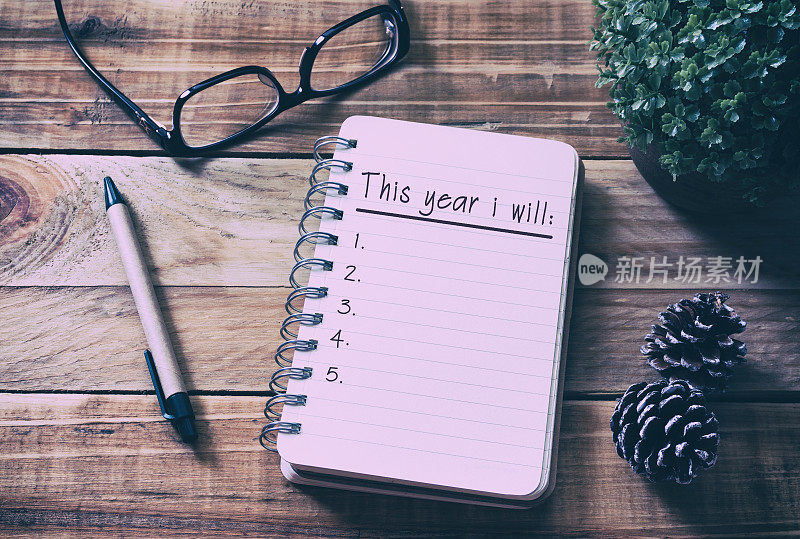 在木头桌上的记事本上写下新年决心清单