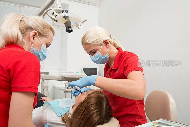 牙科诊所的牙医小组为女病人准备治疗。牙医和助手在过程中