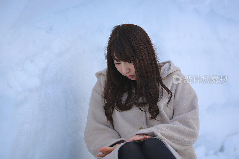 年轻女子坐在雪洞里