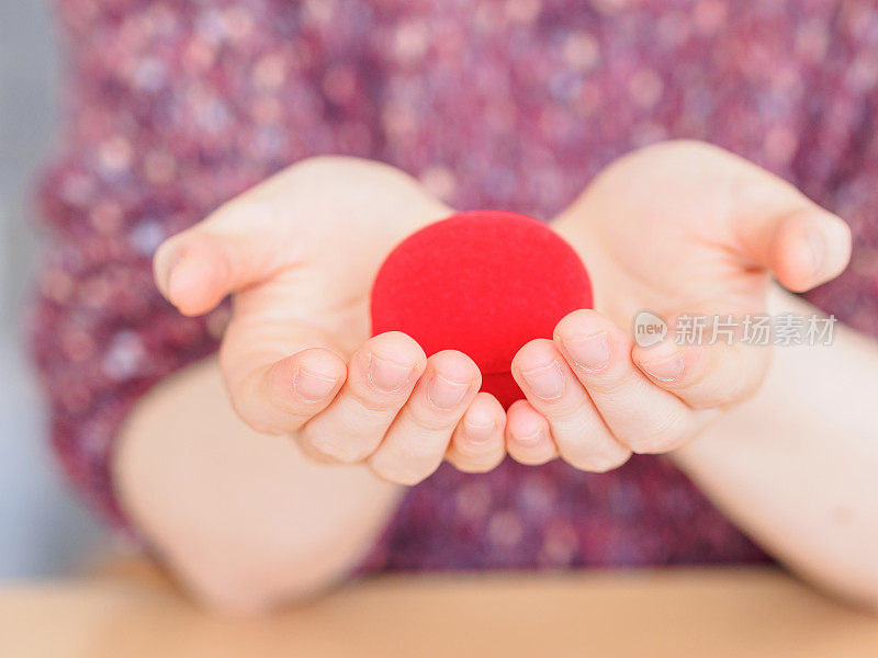 红色礼品盒在女人的手中，像心形。订婚礼物的概念。情人节惊喜礼物，爱的象征。