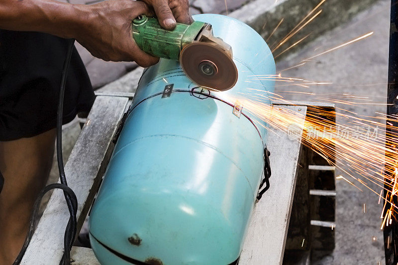 工人们使用金属磨床切割钢制品，产生火花。