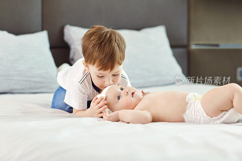 一个小男孩和他的小妹妹在床上又拥抱又亲吻