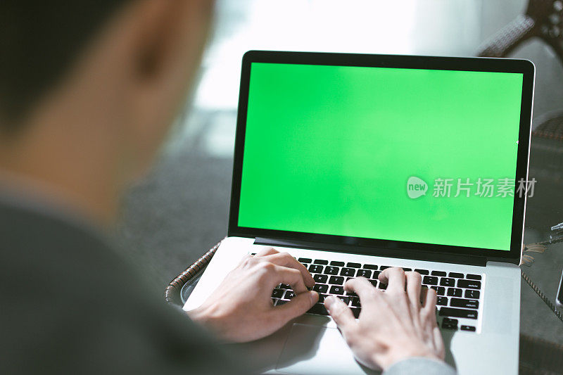 年轻的中国男子用电脑绿屏工作