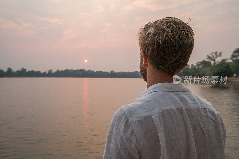 一个年轻人在柬埔寨的湖边凝视夕阳