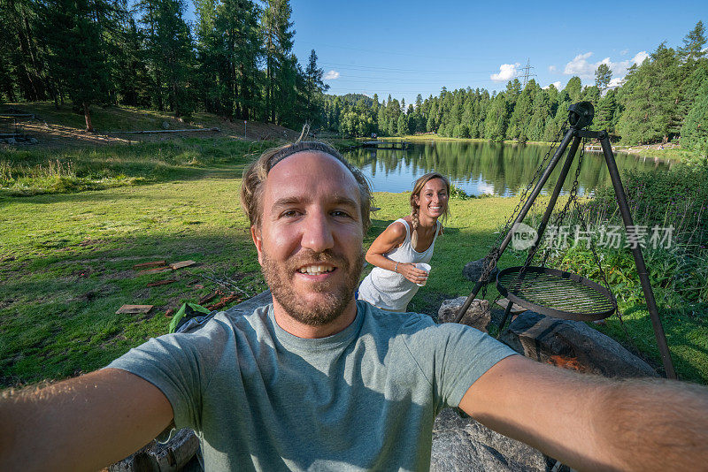 年轻夫妇在夏天的湖边烧烤的自拍