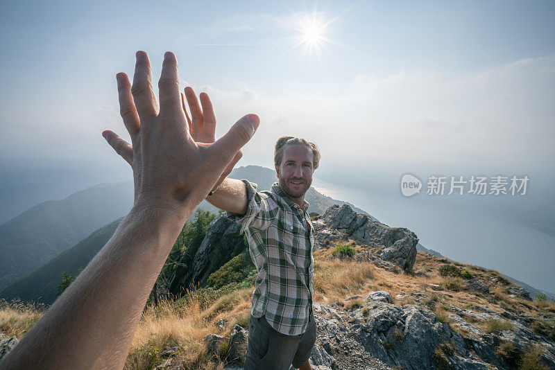 两个徒步旅行者在山顶击掌庆祝的个人视角