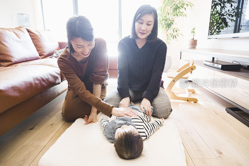 两个女人在客厅给男婴按摩