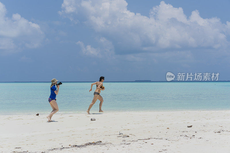 4月，美丽的女人在水边散步，在小岛屿的海滩上拍照