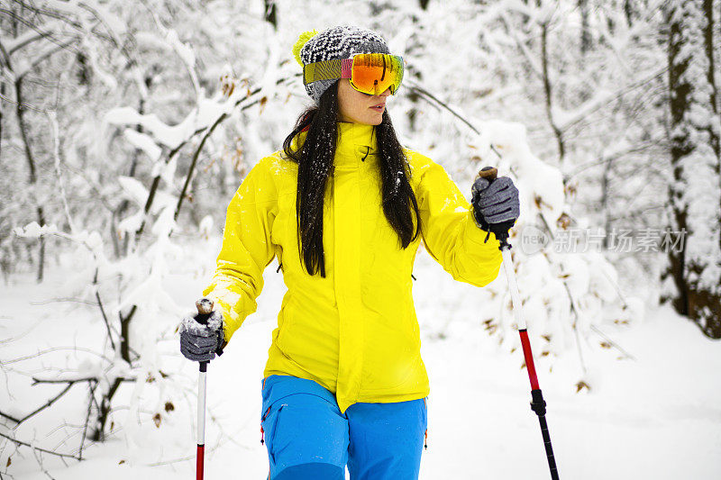 女人徒步旅行者用她的雪鞋和徒步旅行的杆子穿越在一个冰冻的荒野的深雪