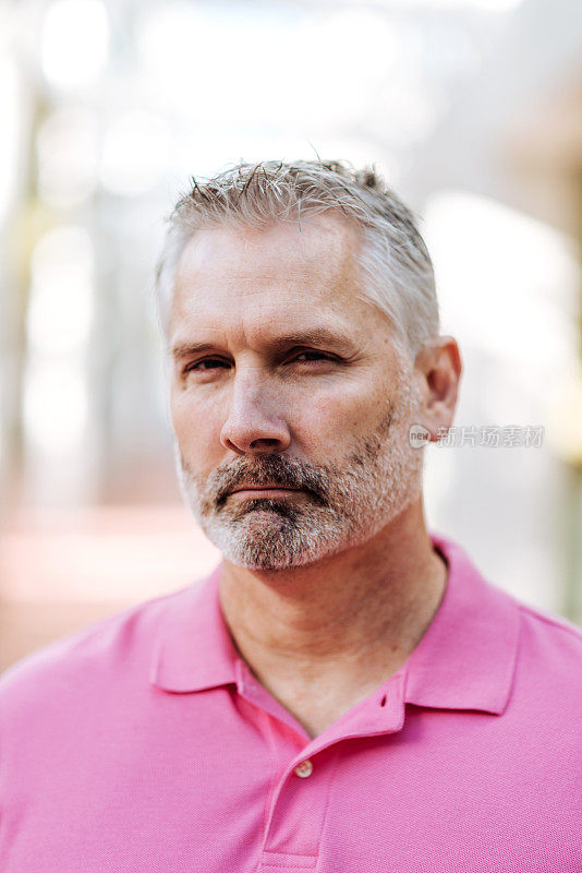成年白人男子的肖像与灰色头发在粉红色polo衫与悲伤的面部表情
