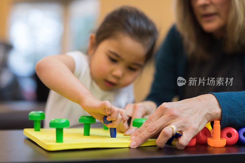 职业治疗师与一个年轻的民族女孩一起工作